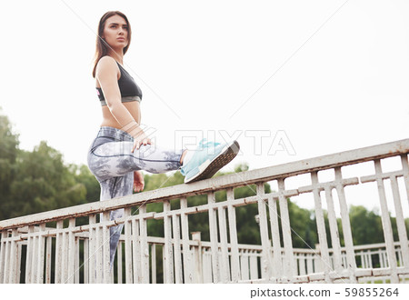 A beautiful athlete brunette performs outdoor exercises 59855264