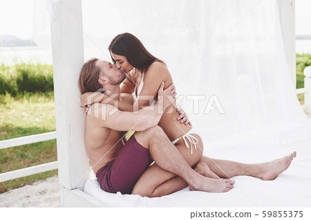 A beautiful couple relaxing on the sandy beach, wearing bathing clothes. Romantic atmosphere 59855375