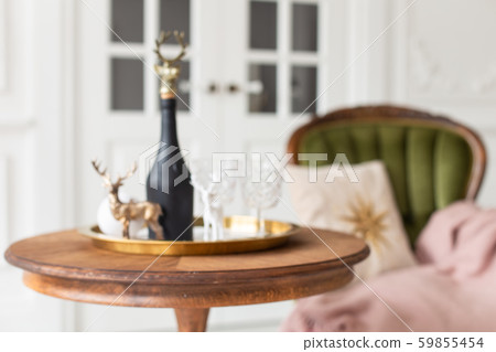 Blured closeup of chamoagne bottle standing on the table next to green armchair 59855454