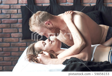 Attractive young lovers have couples playing together in bed, wearing sexy lingerie in a hotel room. 59856153