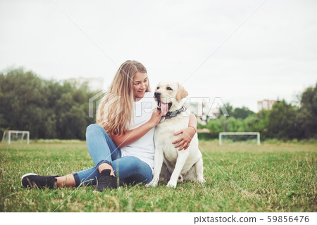 Attractive young woman with labrador outdoors. Woman on a green grass with dog labrador retriever 59856476