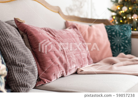 Closeup of pilows laying on sofa with decorated christmas tree on background. Selective focus 59857238
