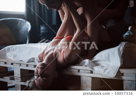 A portrait of a happy young couple who relax in a cozy bed, looking at the camera, smiles fun A portrait of a happy young couple who relax in a cozy bed, looking at the camera, smiles fun 59857316