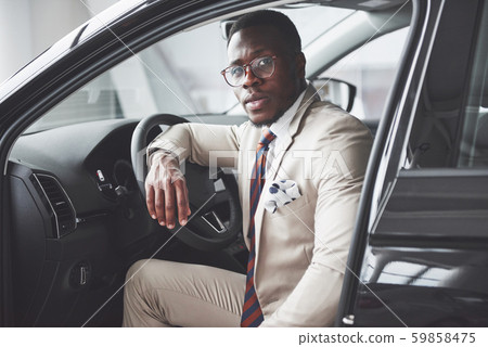 Stylish black businessman sitting behind the wheel of new luxury car. Rich african american man Stylish black businessman sitting behind the wheel of new luxury car. Rich african american man 59858475