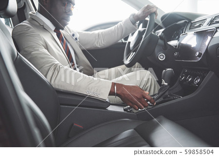 Stylish black businessman sitting behind the wheel of new luxury car. Rich african american man Stylish black businessman sitting behind the wheel of new luxury car. Rich african american man 59858504