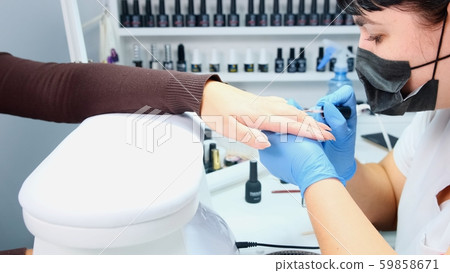 Manicurist makes gel polish on the nails of a clint, close-up Manicurist makes gel polish on the nails of a clint, close-up 59858671