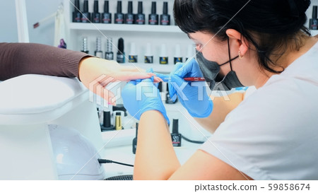 Manicurist paints the nails of a beautiful hand in a beauty salon. Gel polish. Lacquer. Manicure 59858674