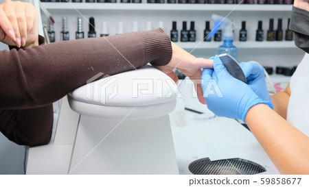 Manicurist files a nail with a nail file to a client. Manicure process, nail extension. close-up Manicurist files a nail with a nail file to a client. Manicure process, nail extension. close-up 59858677