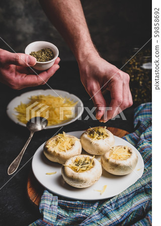 Sprinkling spices on the stuffed button mushrooms Sprinkling spices on the stuffed button mushrooms 59858692