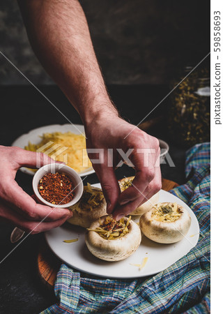 Sprinkling spices on the stuffed button mushrooms Sprinkling spices on the stuffed button mushrooms 59858693