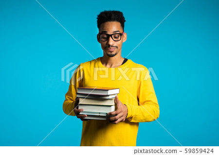 African student is dissatisfied with amount of homework,books. Man in glasses African student is dissatisfied with amount of homework,books. Man in glasses 59859424