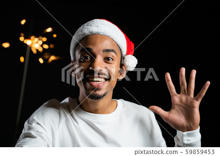 African american man in Santa hat celebrating with sparkler and bengal fire.  59859453