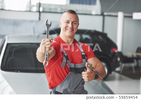 Hands of car mechanic with wrench in garage 59859454