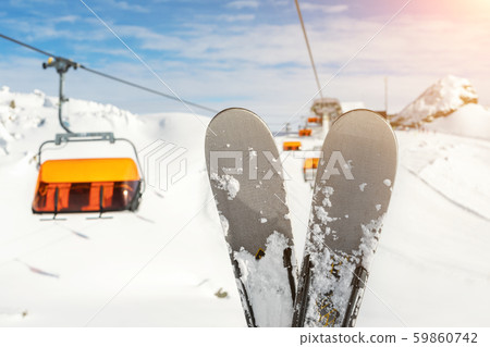 Close-up pair of skis on mountain winter resort with ski-lift and beautiful winter mountain Close-up pair of skis on mountain winter resort with ski-lift and beautiful winter mountain 59860742