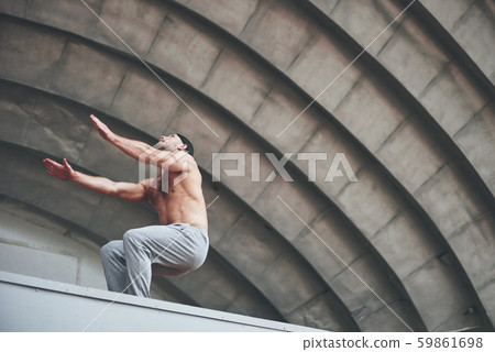 The man outdoors practices parkour, extreme acrobatics. The man outdoors practices parkour, extreme acrobatics. 59861698