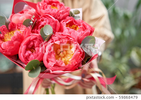 Mono bouquet of peonies, coral charm, in womans hands. Modern floral shop. Finished work of the 59868479