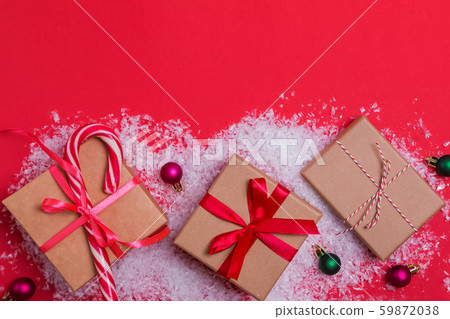 Christmas gift boxes and small balls on red background with decorative snow Christmas gift boxes and small balls on red background with decorative snow 59872038
