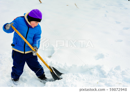 Smiling boy is carrying snow on a shovel, Child 59872948