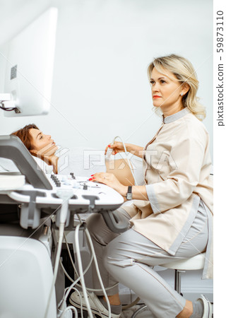 Doctor performs ultrasound examination of a woman 59873110