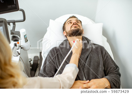 Men examining his thyroid with ultrasound Men examining his thyroid with ultrasound 59873429