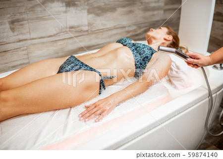 Woman lying under the hot shower in the spa 59874140