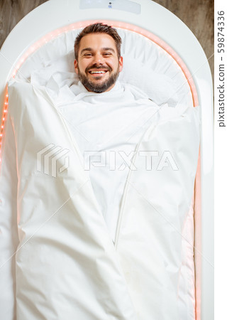 Wrapped man lying in the spa capsule Wrapped man lying in the spa capsule 59874336