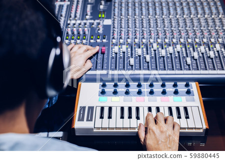 back of asian male musician, producer making a song on midi keyboard and mixing audio tracks in home recording studio. music production concept 59880445
