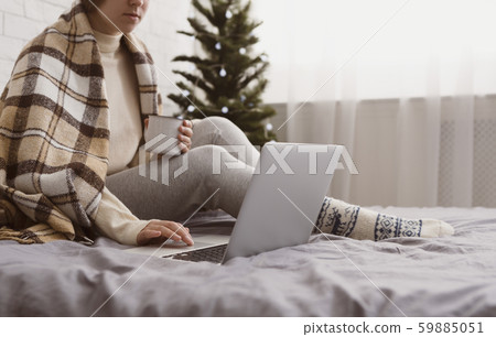 Female in plaid drinking chocolate and searching for Christmas presents 59885051