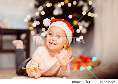Little girl drawing on floor near xmas tree 59885096