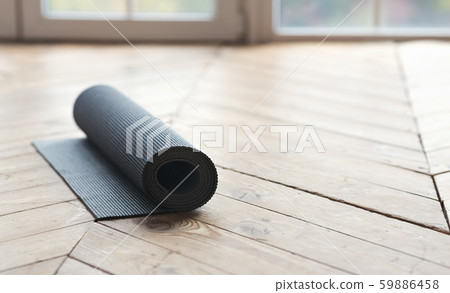 Rolled up fitness mat on wooden floor at yoga studio Rolled up fitness mat on wooden floor at yoga studio 59886458