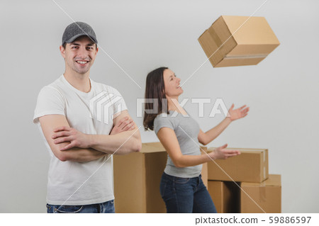 Strong delivery man transported boxes into new apartment of lovely young woman and is standing on 59886597