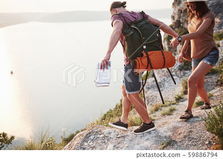 Two tourist with backpacks climb to the top of the mountain and enjoying sunrise 59886794