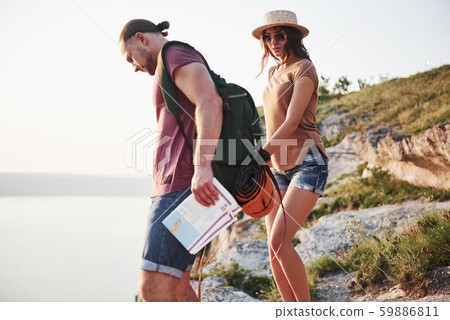 Two tourist with backpacks climb to the top of the mountain and enjoying sunrise Two tourist with backpacks climb to the top of the mountain and enjoying sunrise 59886811