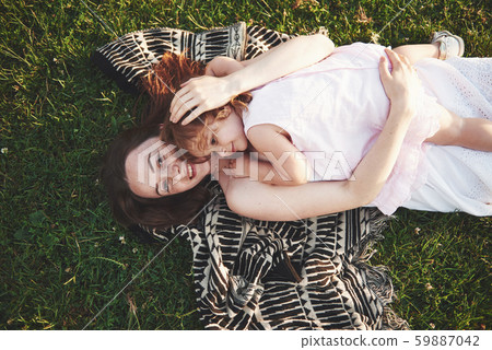 Happy girl and her mom have fun in the open air on green grass. 59887042