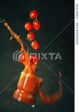 glass of tomato juice falls with tomatoes. 59887844