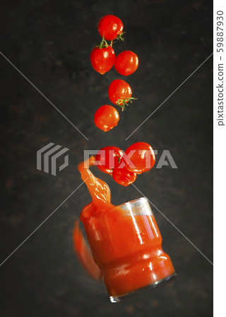 glass of tomato juice falls with tomatoes. 59887930