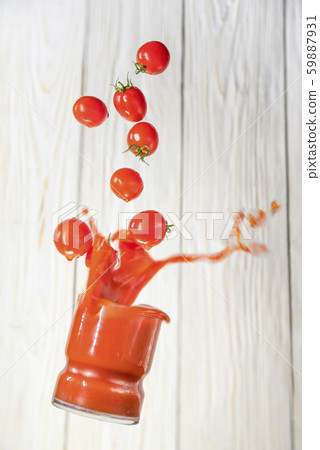 glass of tomato juice falls with tomatoes. 59887931