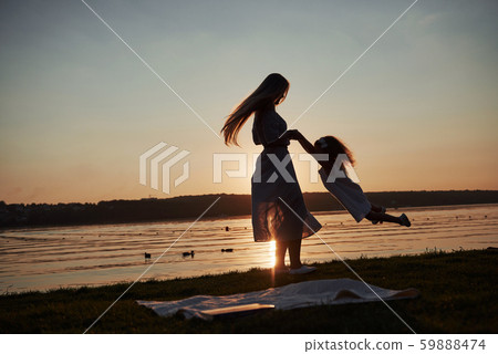 Mom plays with her baby on holidays near the ocean, silhouettes at sunset 59888474