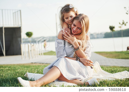 Happy young mother with a playful daughter in a park near the water 59888618
