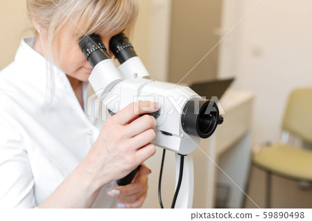 Female blond doctor gynecologist looks through a 59890498