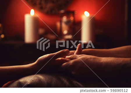A man makes a woman acupressure fingers. hand massage with intimate lighting. Prelude before making A man makes a woman acupressure fingers. hand massage with intimate lighting. Prelude before making 59890512