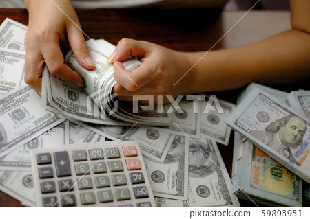 Businessmen women counting money on a stack of 100 US dollars banknotes lots of money Businessmen women counting money on a stack of 100 US dollars banknotes lots of money 59893951