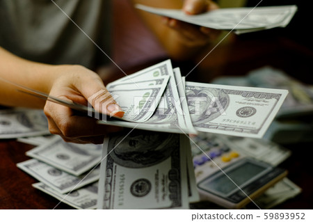 Businessmen women counting money on a stack of 100 US dollars banknotes lots of money Businessmen women counting money on a stack of 100 US dollars banknotes lots of money 59893952