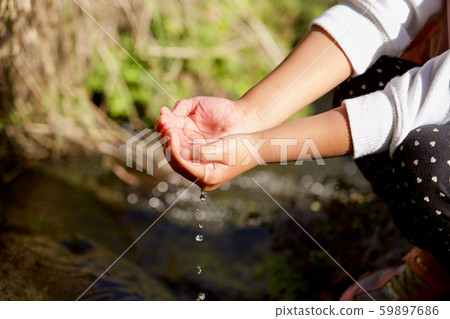 Girl scooping water from the river 59897686