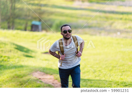 Hiking man portrait with backpack walking in nature. Caucasian man smiling happy with forest in Hiking man portrait with backpack walking in nature. Caucasian man smiling happy with forest in 59901231