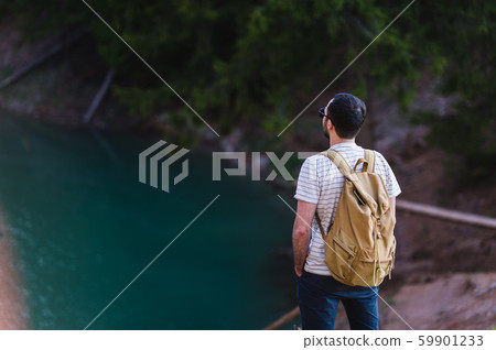 Guy standing on the cliff above the lake with the sky reflecting in it Guy standing on the cliff above the lake with the sky reflecting in it 59901233