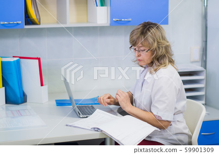 Happy senior doctor with clipboard at hospital reception 59901309