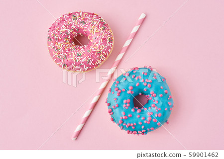 Two donuts separated with a drinking straw on pink Two donuts separated with a drinking straw on pink 59901462