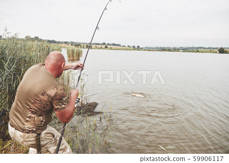 The fisherman caught a big fish of the carp and pulled it to the shore. Hunting and hobby sport 59906117