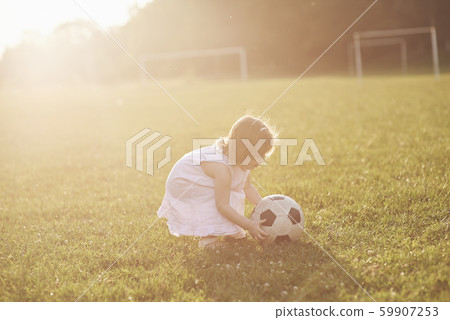 little girl is playing ball in the field at sunset 59907253